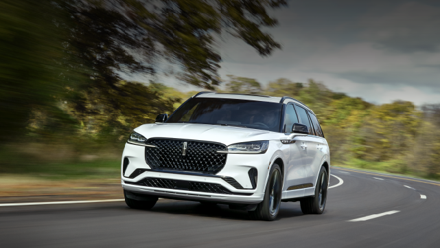 A white 2025 Lincoln Aviator® SUV is being driven down a road lined with trees. | Dave Sinclair Lincoln St. Peters in Saint Peters MO