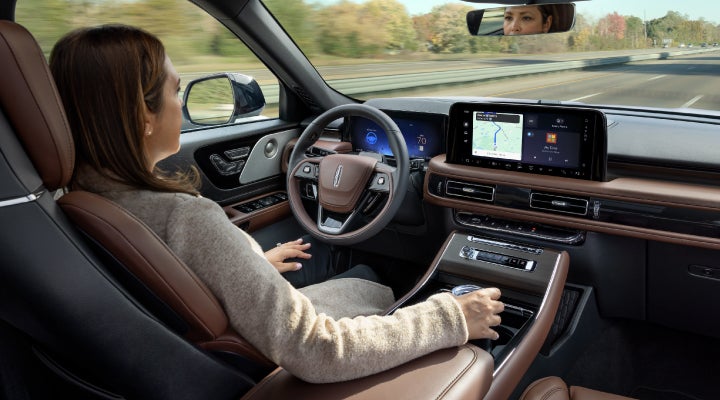 A 2026 Lincoln Aviator® SUV is being driven hands-free on a highway near a forest | Dave Sinclair Lincoln St. Peters in Saint Peters MO