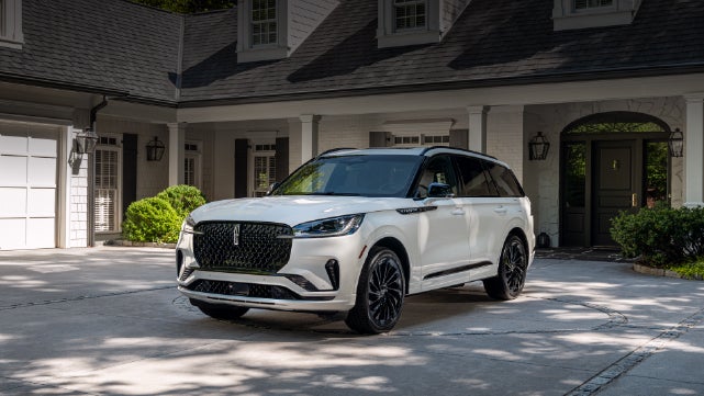 A white 2026 Lincoln Aviator® SUV is parked in the driveway of a luxury home. | Dave Sinclair Lincoln St. Peters in Saint Peters MO