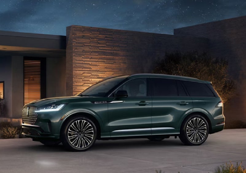 A green 2027 Lincoln Aviator® SUV is parked outside a contemporary home. | Dave Sinclair Lincoln St. Peters in Saint Peters MO