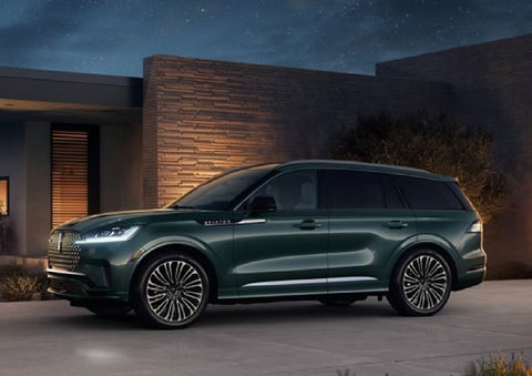 A green 2027 Lincoln Aviator® SUV is parked outside a contemporary home. | Dave Sinclair Lincoln St. Peters in Saint Peters MO