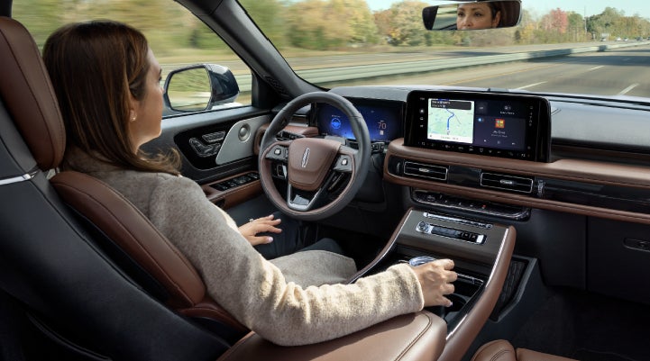 A 2027 Lincoln Aviator® SUV is being driven hands-free on a highway lined with trees. | Dave Sinclair Lincoln St. Peters in Saint Peters MO