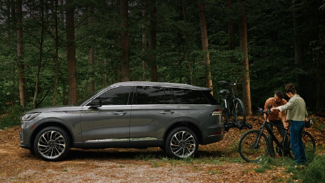 A father and son load e-bikes on a bike rack attached to a 2027 Lincoln Aviator® SUV. | Dave Sinclair Lincoln St. Peters in Saint Peters MO