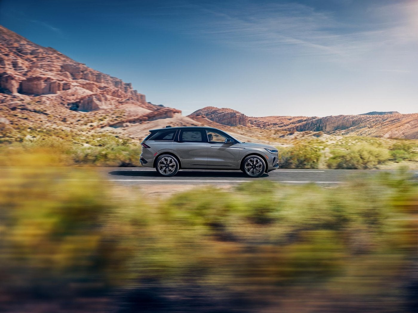Lincoln Nautilus driving fast on a desert highway past rocky hills