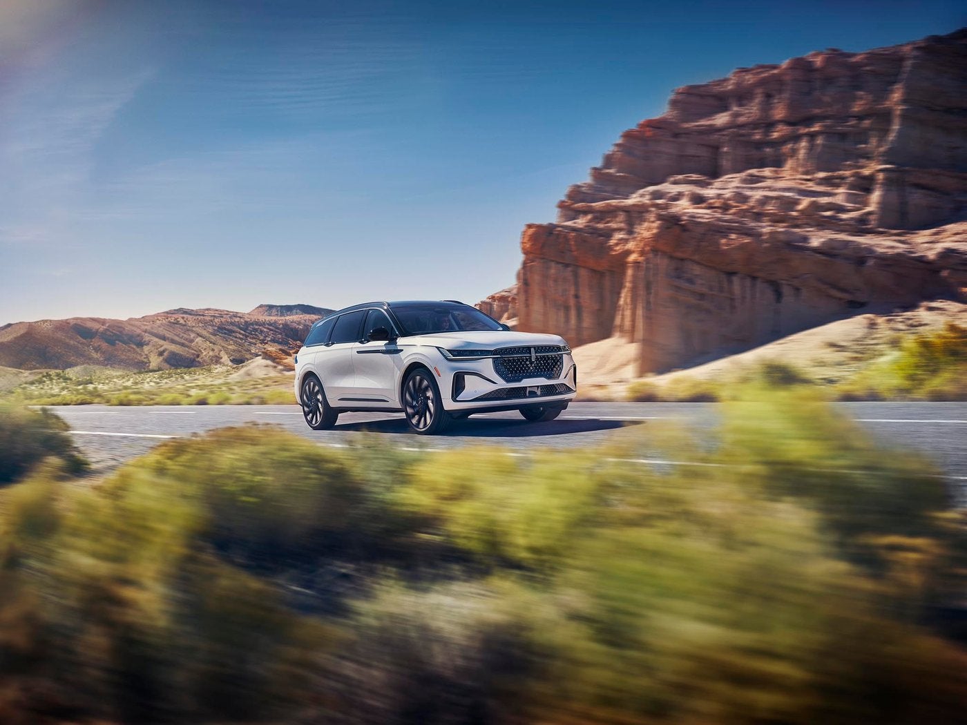 White Lincoln Nautilus driving on a highway past red rock cliffs