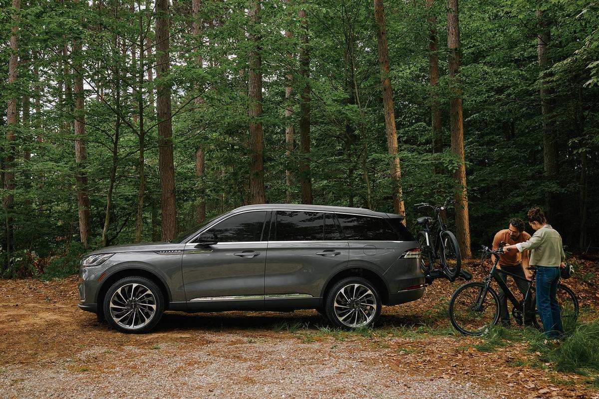 Father and son loading bicycles onto a hitch rack on a Lincoln Aviator
