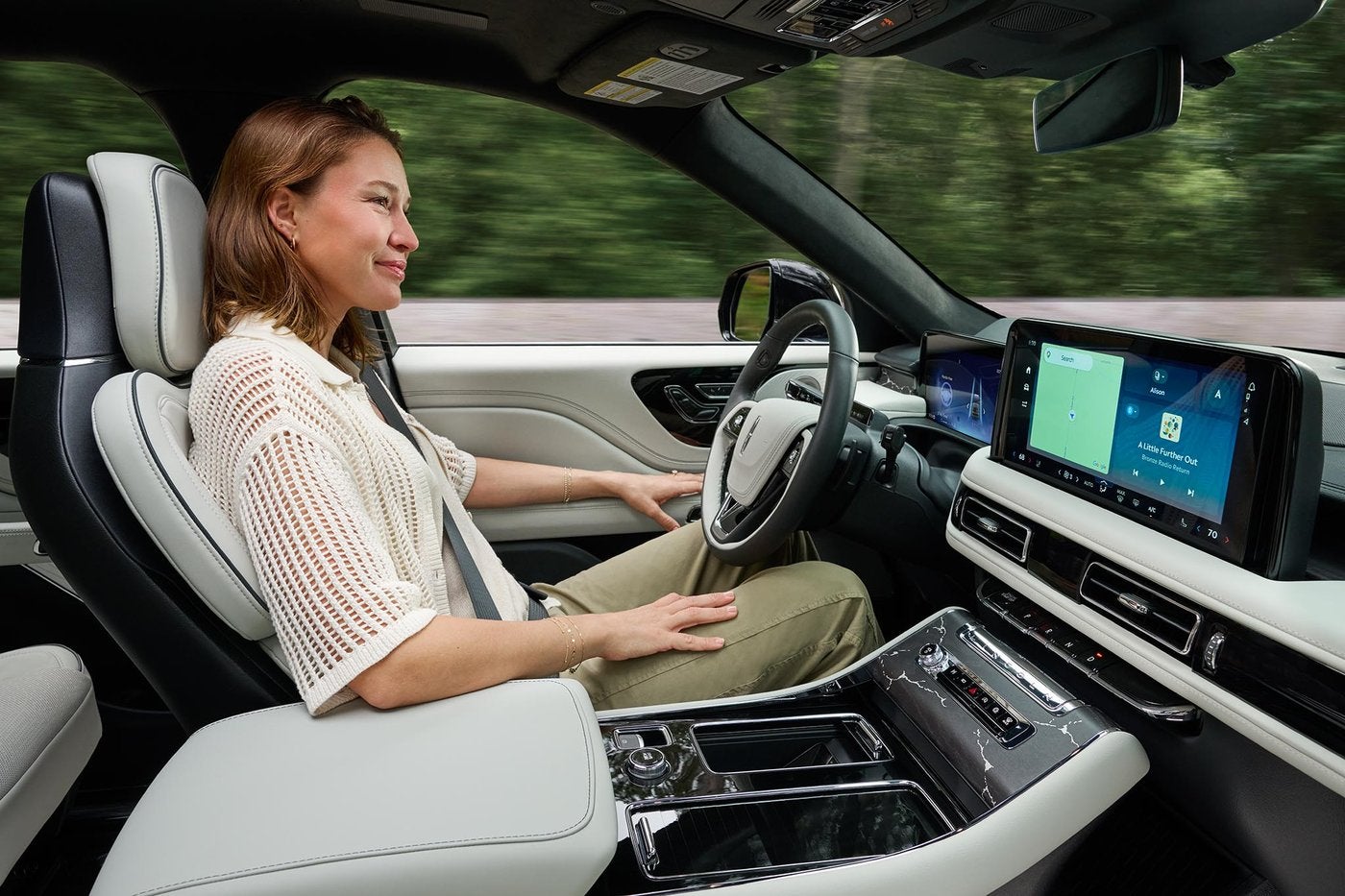 Woman driving a Lincoln Aviator on the highway with her hands off the wheel