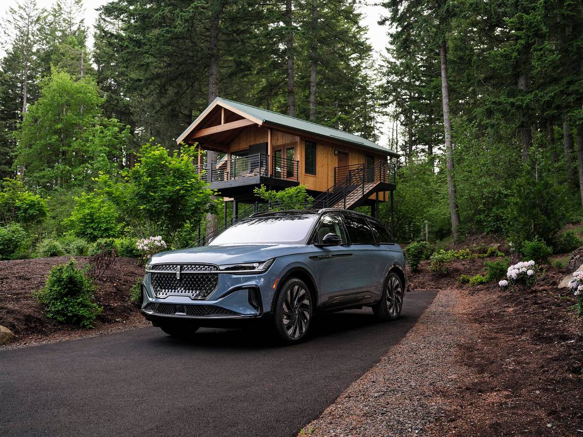 Blue gray Lincoln Nautilus parked on a home driveway in front of a wooded cabin