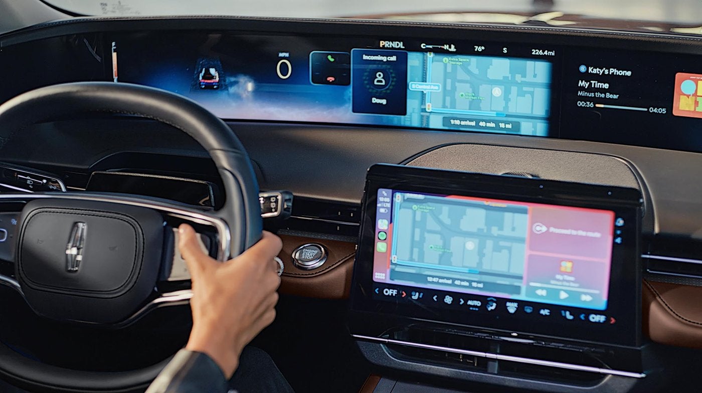Driver hand on a Lincoln Nautilus steering wheel with the digital display ahead